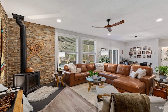 living room featuring light hardwood / wood-style flooring, a wood stove, and ceiling fan