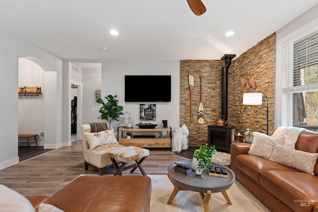 living room featuring a wood stove, hardwood / wood-style flooring, and ceiling fan