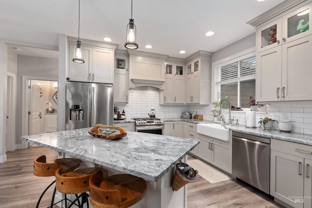 kitchen featuring a kitchen island, sink, a breakfast bar, appliances with stainless steel finishes, and tasteful backsplash