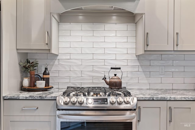 kitchen featuring stainless steel gas stove, light stone countertops, extractor fan, and tasteful backsplash