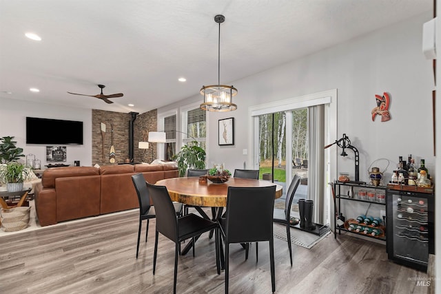 dining space with hardwood / wood-style floors, beverage cooler, and ceiling fan with notable chandelier