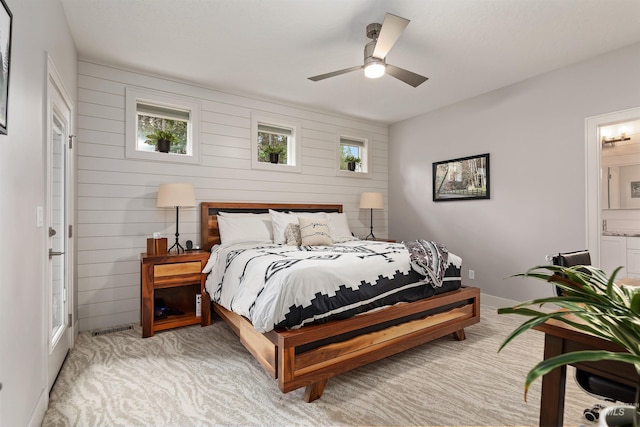 bedroom featuring light carpet, ensuite bathroom, and ceiling fan