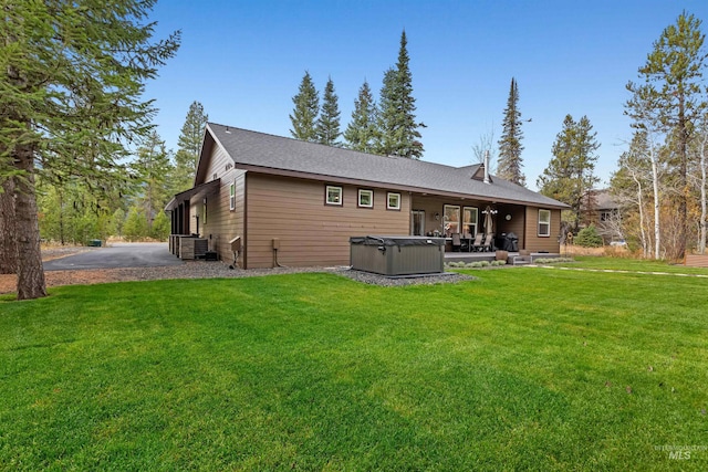 back of house featuring a yard, a hot tub, and a patio area