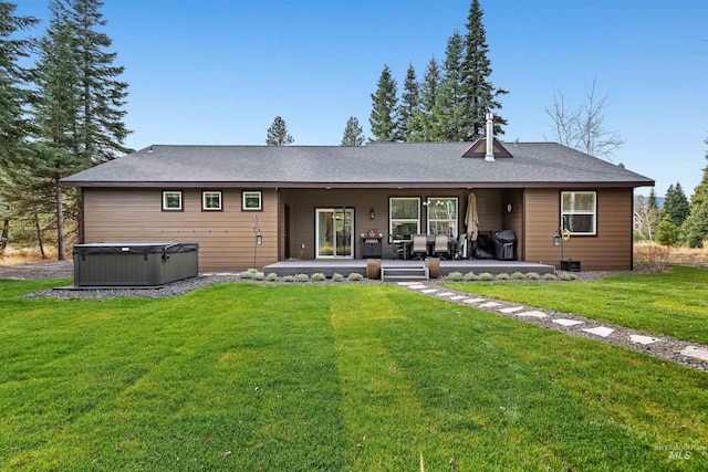 back of property with a patio, a hot tub, and a lawn