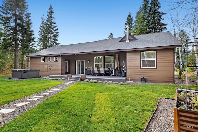 rear view of property with a hot tub, a yard, and a patio