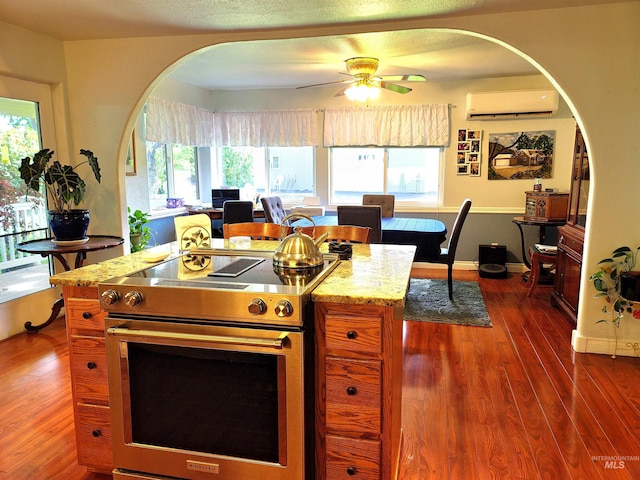 27406 Gem Ln, Juliaetta, ID 83535 - kitchen featuring electric range, a wall unit AC, arched walkways, ceiling fan, and wood finished floors