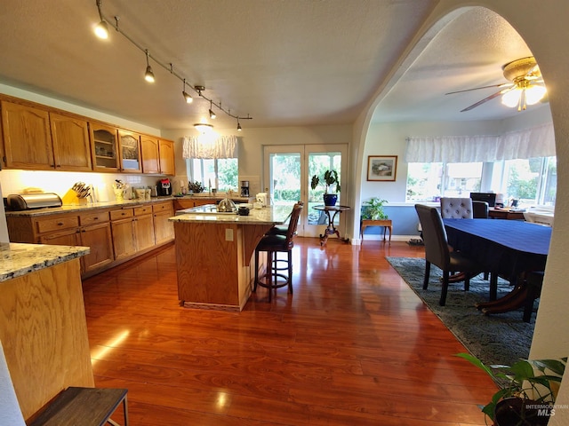 27406 Gem Ln, Juliaetta, ID 83535 - kitchen featuring a breakfast bar, dark wood-style flooring, glass insert cabinets, and light stone countertops