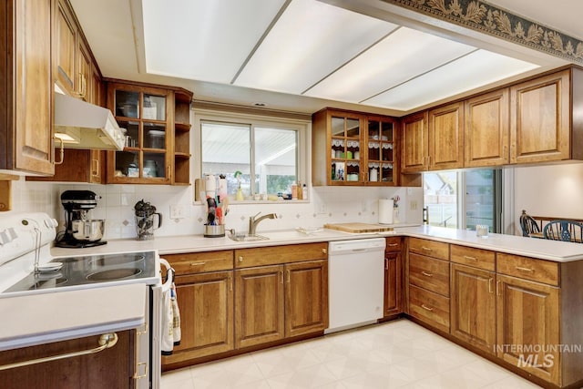 11360 W Lake Hazel Rd, Boise, ID 83709 - kitchen featuring white appliances, under cabinet range hood, brown cabinets, a peninsula, and backsplash