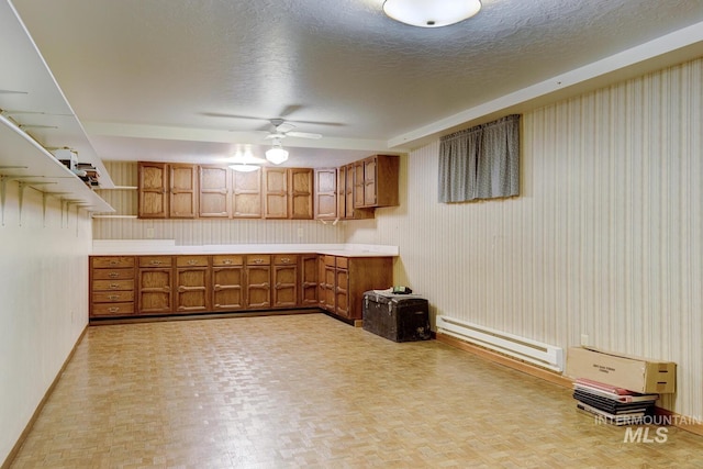 11360 W Lake Hazel Rd, Boise, ID 83709 - kitchen with brown cabinetry, a baseboard heating unit, baseboards, light countertops, and ceiling fan