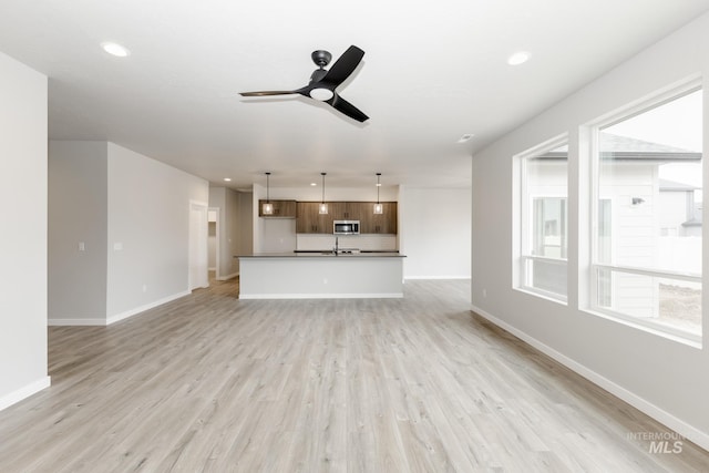 unfurnished living room featuring ceiling fan and light hardwood / wood-style floors