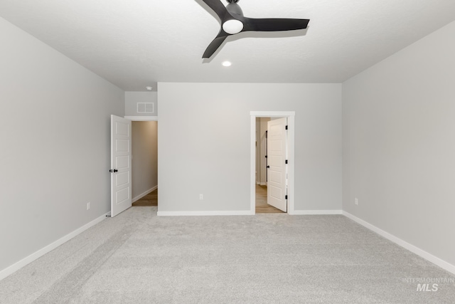 unfurnished bedroom featuring ceiling fan, light carpet, and a textured ceiling