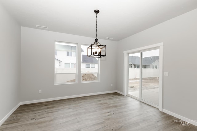 unfurnished dining area featuring a chandelier and light wood-type flooring