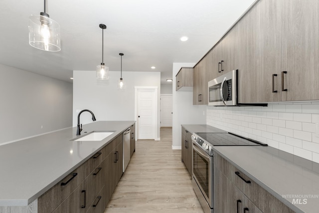 kitchen featuring sink, decorative light fixtures, decorative backsplash, and appliances with stainless steel finishes