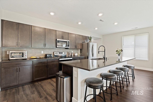 kitchen featuring appliances with stainless steel finishes, sink, a breakfast bar, and an island with sink