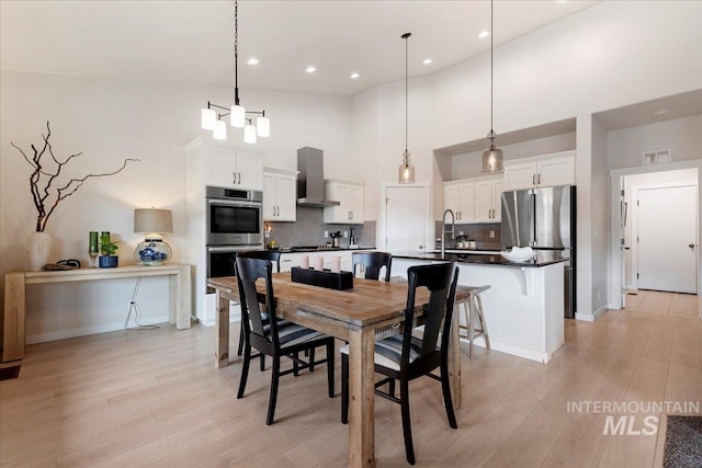 dining space with a high ceiling, recessed lighting, visible vents, and light wood-style floors