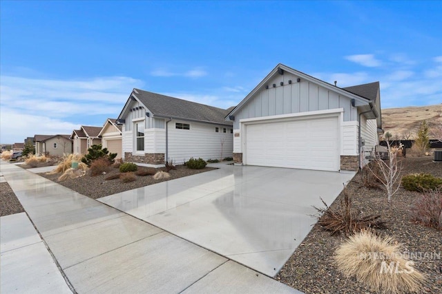 view of front of home featuring board and batten siding, stone siding, an attached garage, and concrete driveway