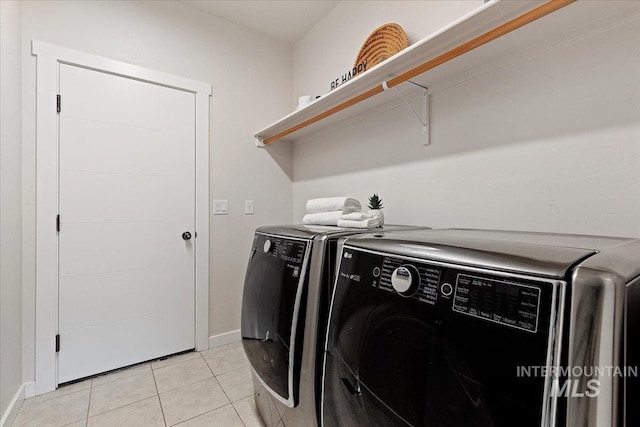 laundry room with laundry area, light tile patterned flooring, washing machine and dryer, and baseboards