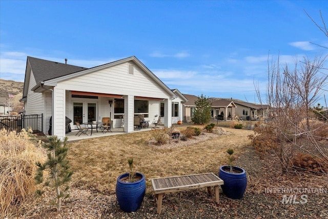 rear view of property featuring fence, a patio, and french doors