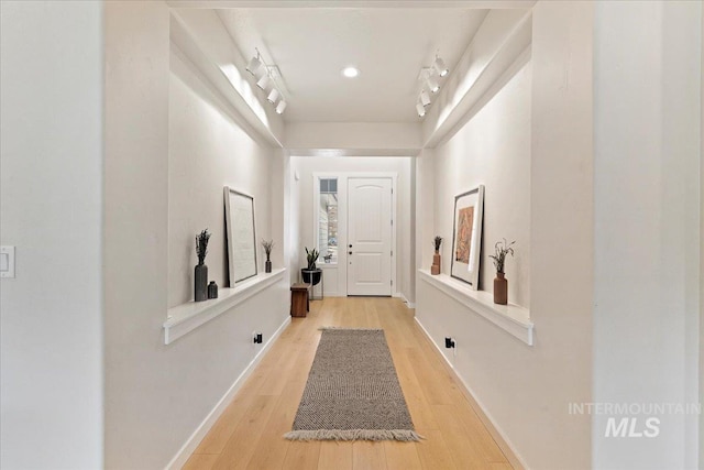 hallway featuring light wood-type flooring and baseboards