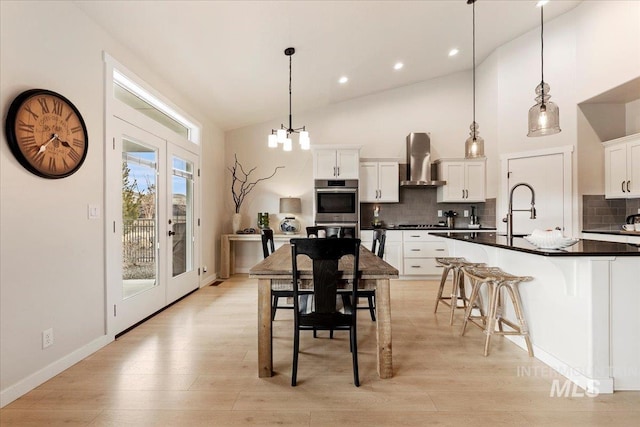 kitchen featuring french doors, dark countertops, a sink, light wood-type flooring, and wall chimney exhaust hood