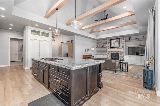 kitchen with ceiling fan, hanging light fixtures, a barn door, built in features, and white cabinets