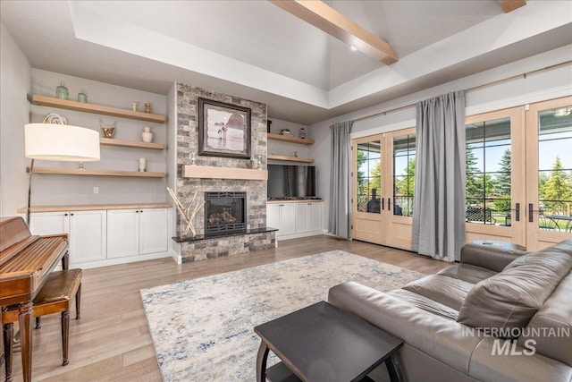 living room with a fireplace, french doors, light wood-type flooring, and a tray ceiling