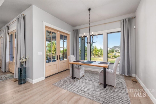 dining space featuring a chandelier, plenty of natural light, light hardwood / wood-style flooring, and french doors