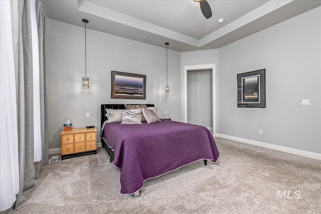 bedroom featuring carpet, a tray ceiling, and ceiling fan