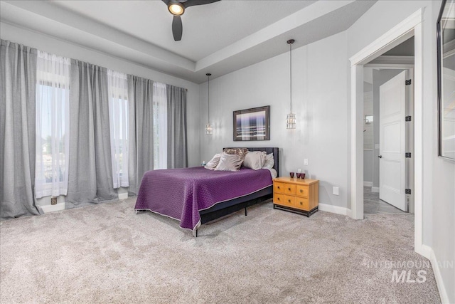 carpeted bedroom featuring a tray ceiling and ceiling fan