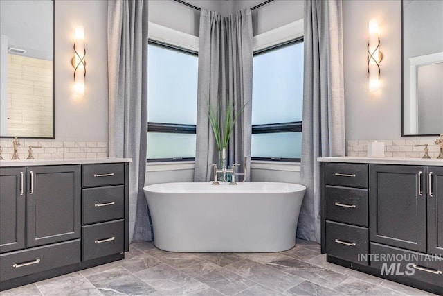 bathroom with decorative backsplash, a washtub, and vanity