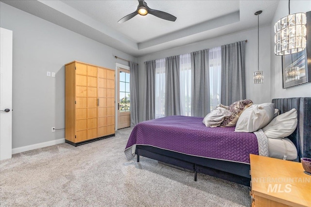 carpeted bedroom featuring a tray ceiling and ceiling fan