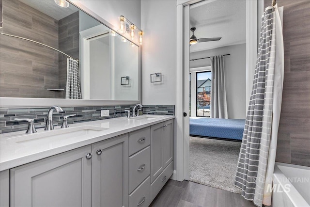 bathroom with backsplash, vanity, ceiling fan, hardwood / wood-style flooring, and shower / bathtub combination with curtain