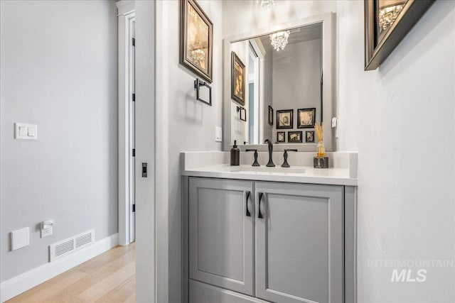 bathroom featuring an inviting chandelier, vanity, and hardwood / wood-style flooring