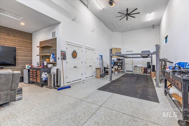 garage featuring ceiling fan and wooden walls