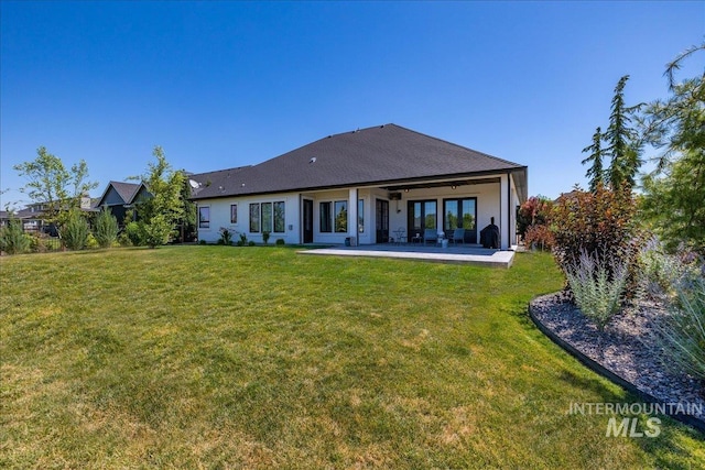 back of property with a lawn and a patio