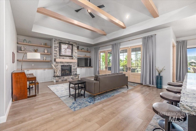 living room with beam ceiling, ceiling fan, french doors, and light hardwood / wood-style flooring