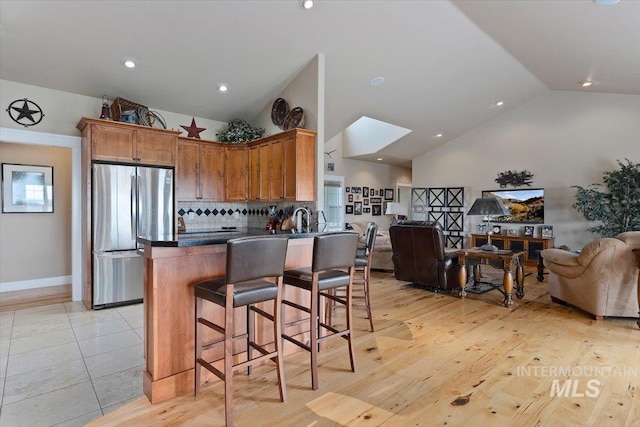 kitchen featuring a breakfast bar area, dark countertops, freestanding refrigerator, open floor plan, and a peninsula