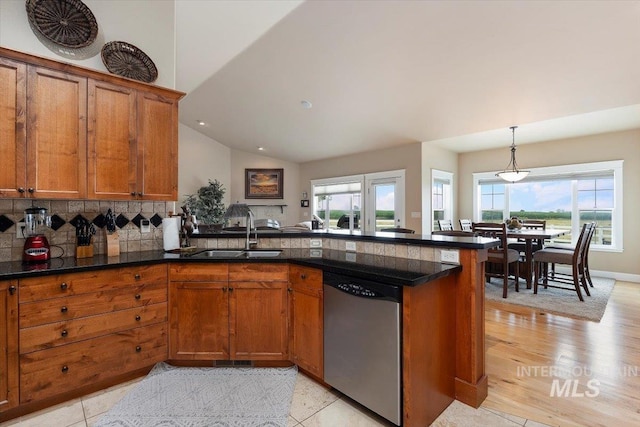 kitchen with a peninsula, stainless steel dishwasher, brown cabinetry, and a sink