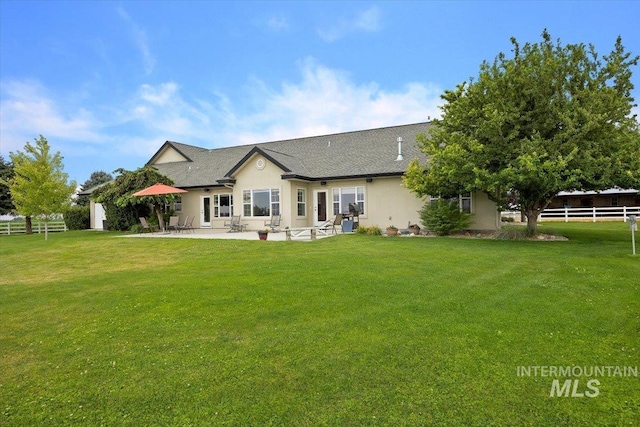 back of property featuring a yard, fence, stucco siding, and a patio