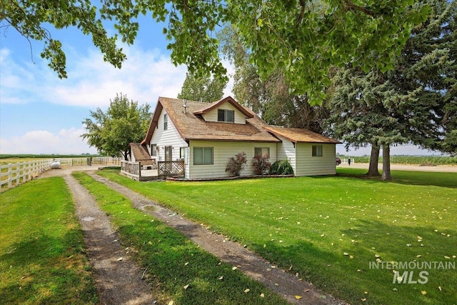 rear view of house featuring fence and a lawn