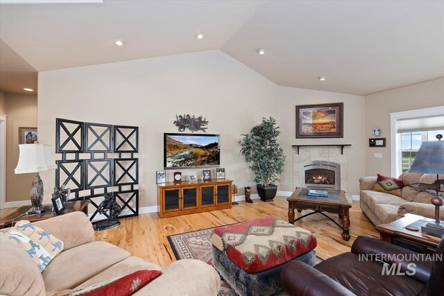 living area with baseboards, a tiled fireplace, wood finished floors, vaulted ceiling, and recessed lighting