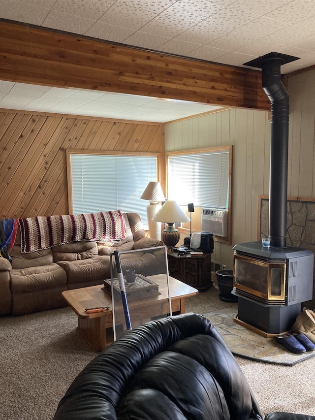 living area with carpet floors, cooling unit, a wood stove, and wooden walls