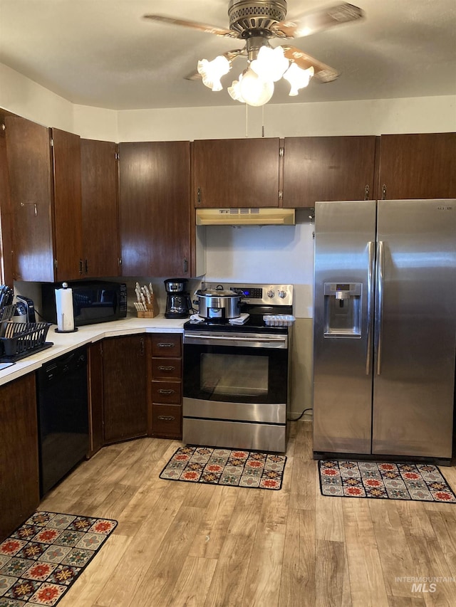 kitchen with stainless steel appliances, light countertops, light wood-style floors, dark brown cabinets, and under cabinet range hood