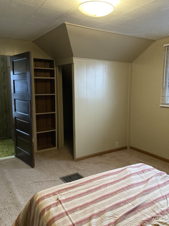 unfurnished bedroom with baseboards, visible vents, vaulted ceiling, and carpet flooring