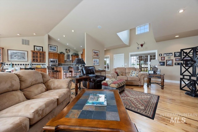 living room featuring light wood finished floors, recessed lighting, visible vents, high vaulted ceiling, and baseboards