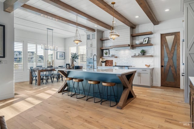 kitchen featuring decorative backsplash, light wood-style flooring, light countertops, and open shelves