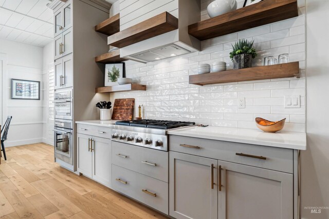 kitchen with custom exhaust hood, gray cabinets, stainless steel gas cooktop, and open shelves