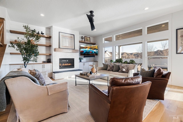 living room with recessed lighting, a fireplace, and light wood finished floors