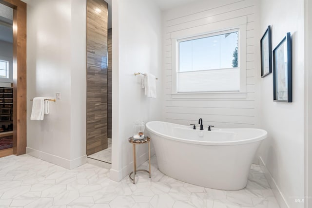 bathroom with marble finish floor, baseboards, a soaking tub, and walk in shower