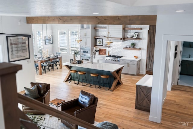 kitchen with open shelves, a kitchen breakfast bar, light wood-style flooring, and light countertops